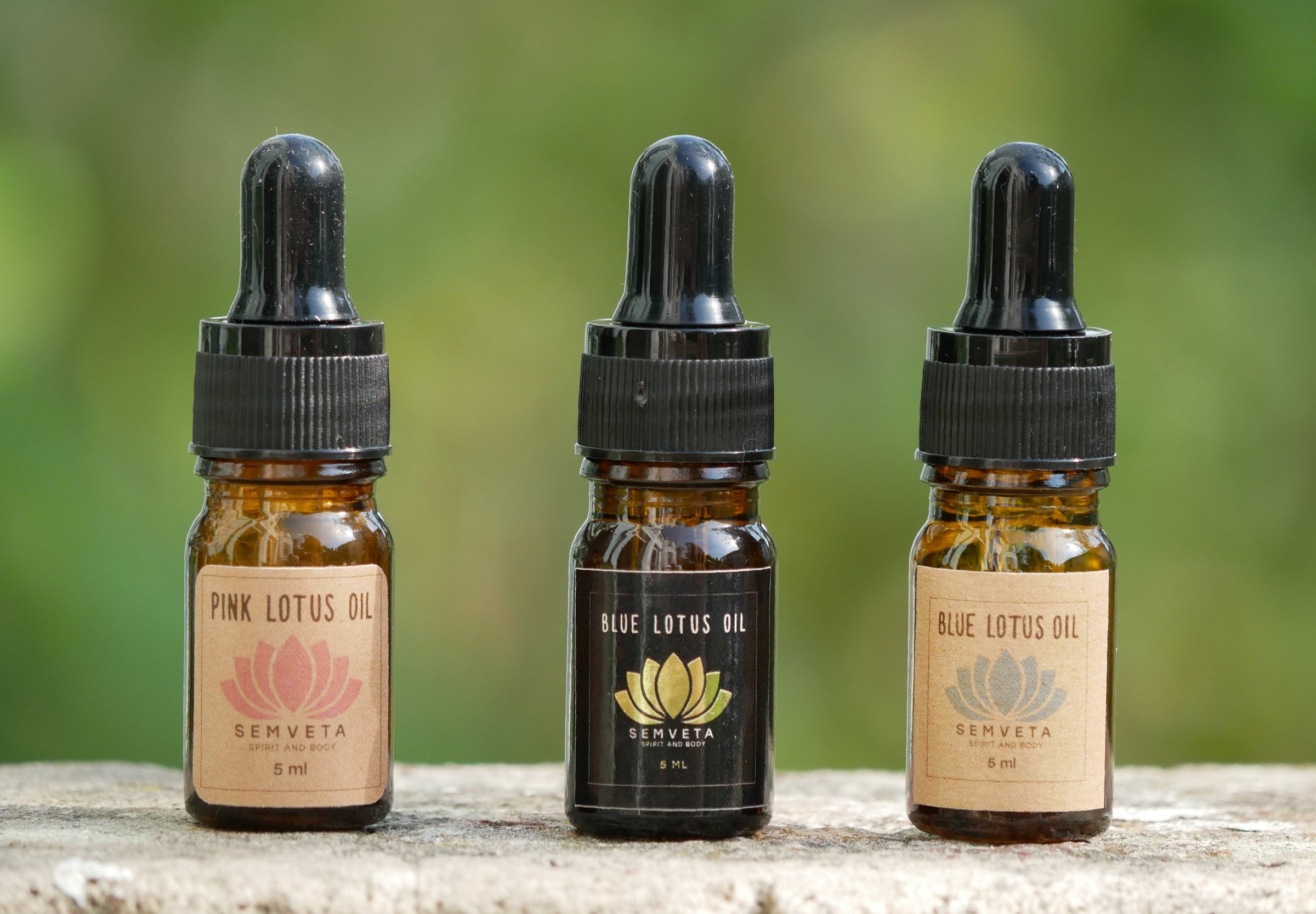 Pink and Blue Lotus Oil bottles for spiritual wellness, 5ml each, with dropper caps on stone surface